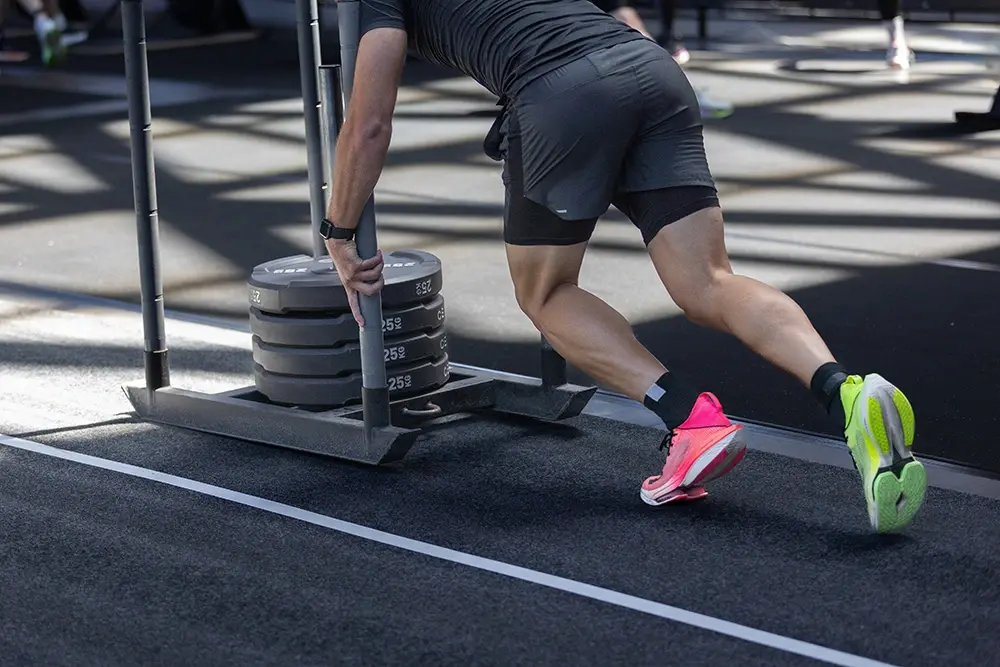 Man training for the HYROX sled push station.