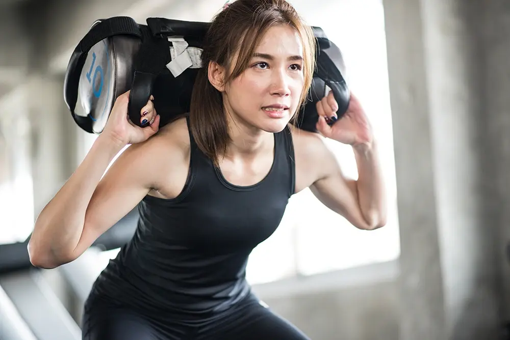 Woman lifting weights in a gym setting while training for HYROX.