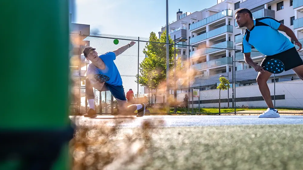 Two athletes playing pickleball on a sunny day.