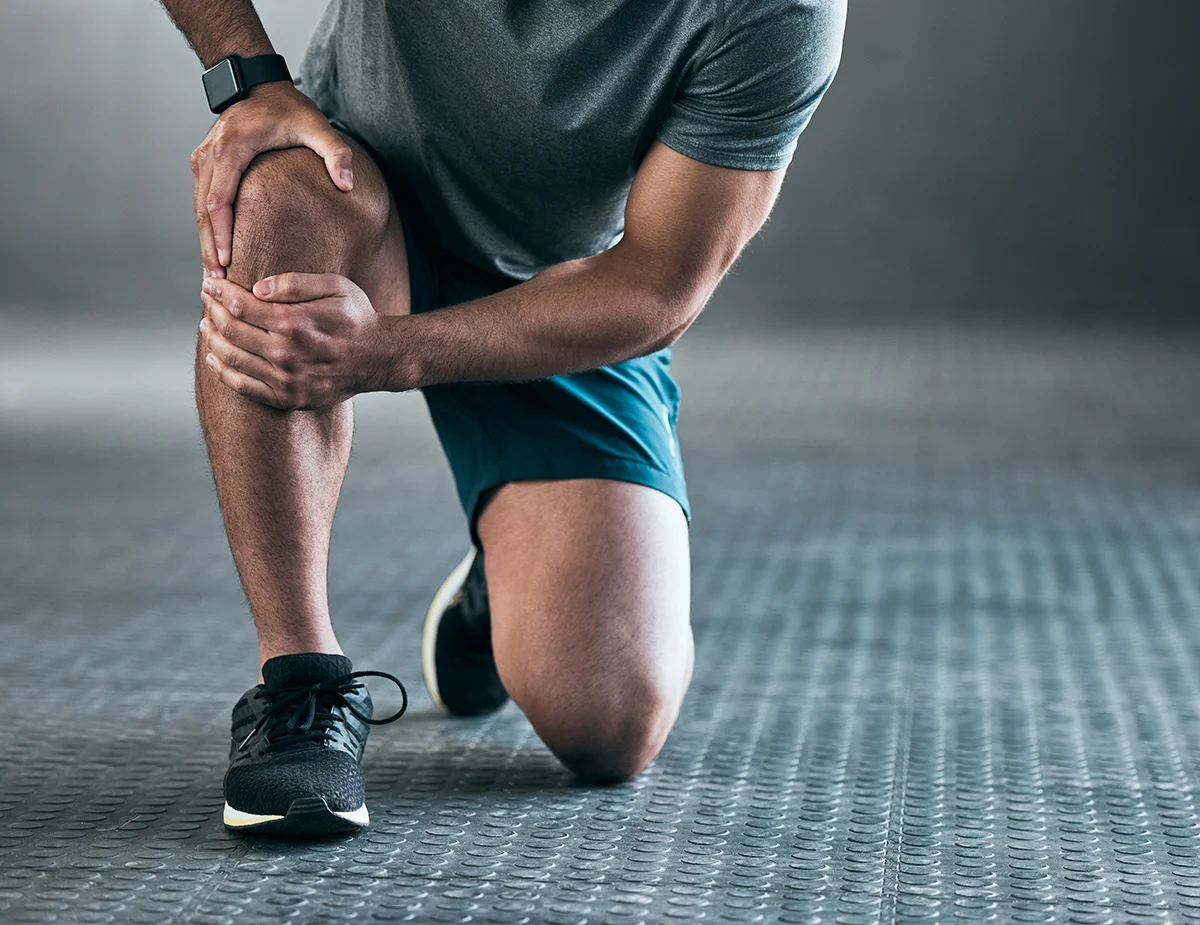 Male athlete holding his knee in pain after an ACL tear during sports