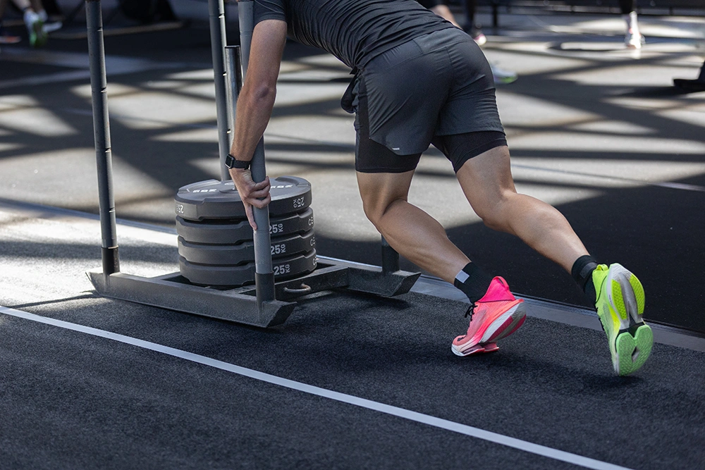 Man training for the HYROX sled push station.