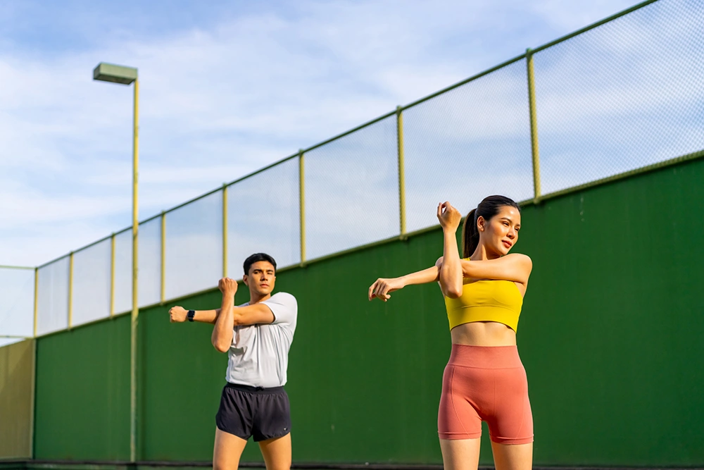 Two athletes stretching on the pickleball court.