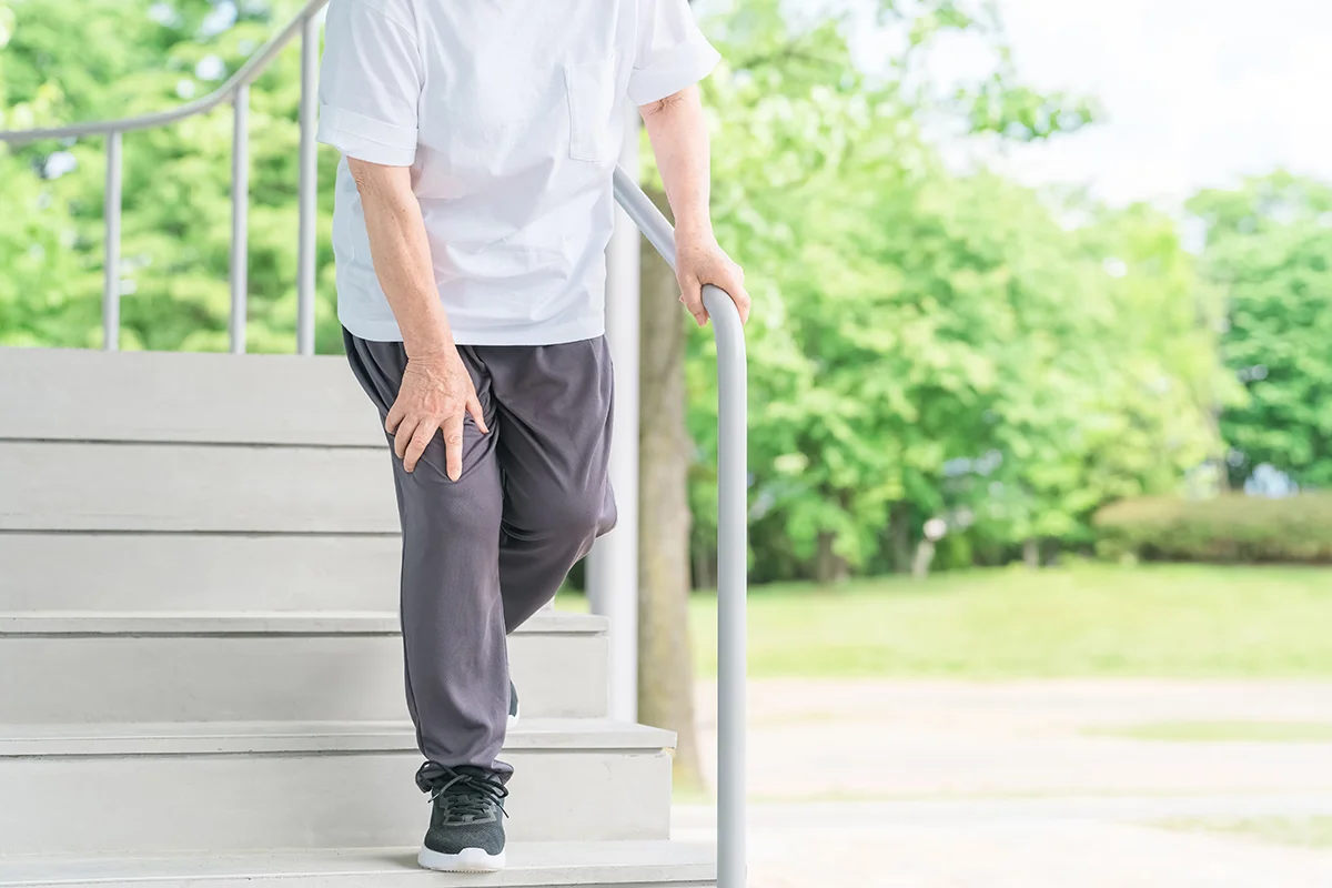 Elderly woman experiencing knee pain while descending stairs