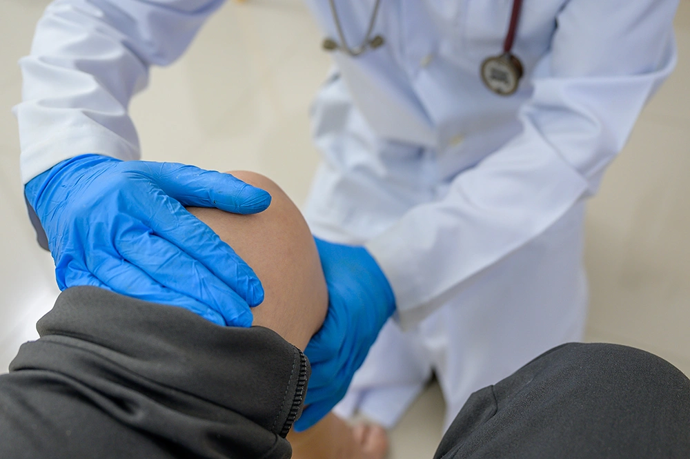 Knee surgeon performing a physical exam of a patient’s knee.