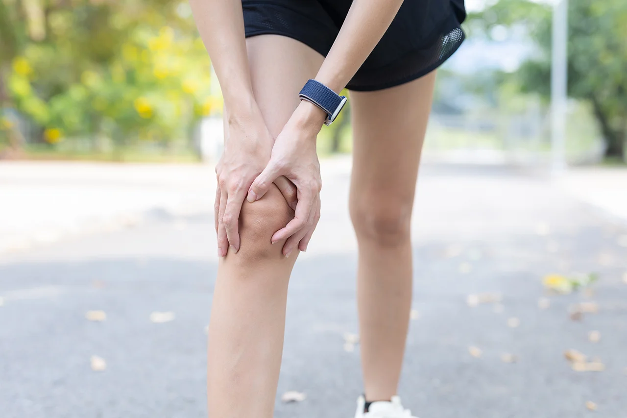 Woman holding her knee due to persistent pain after an injury.